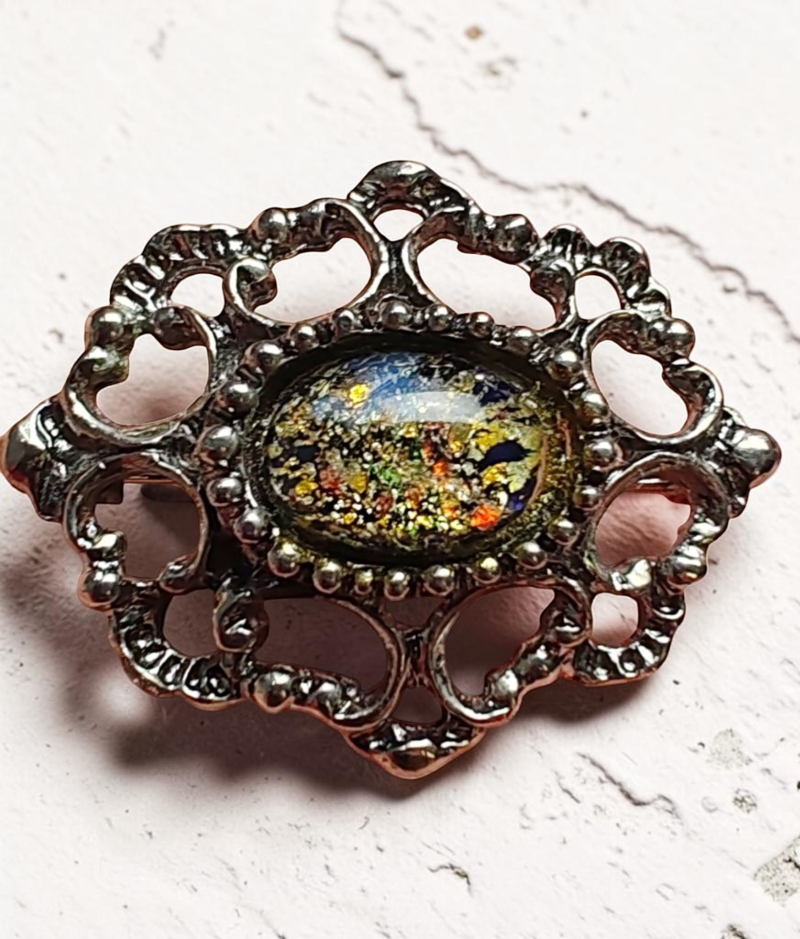 Díszes ovális köves kitűző ezüstszínű alappal