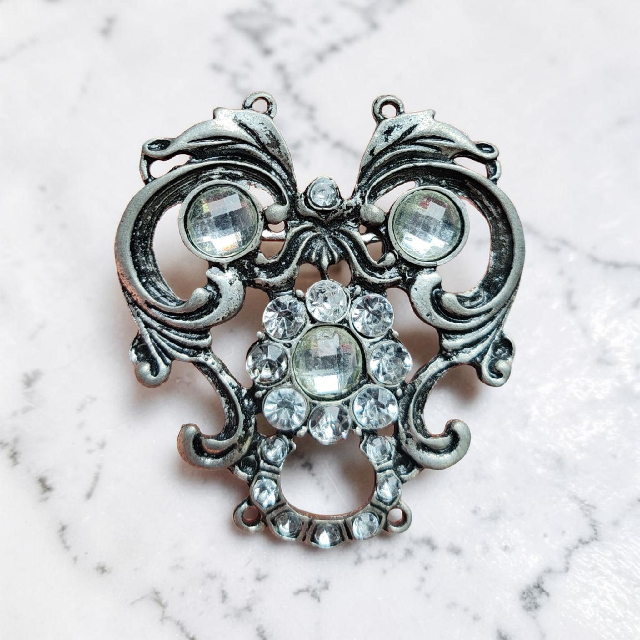 Díszes köves kitűző kopott ezüst hatású alappal